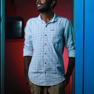 Fashionable young man smiling indoors with a stylish urban backdrop, creating a vibrant mood.